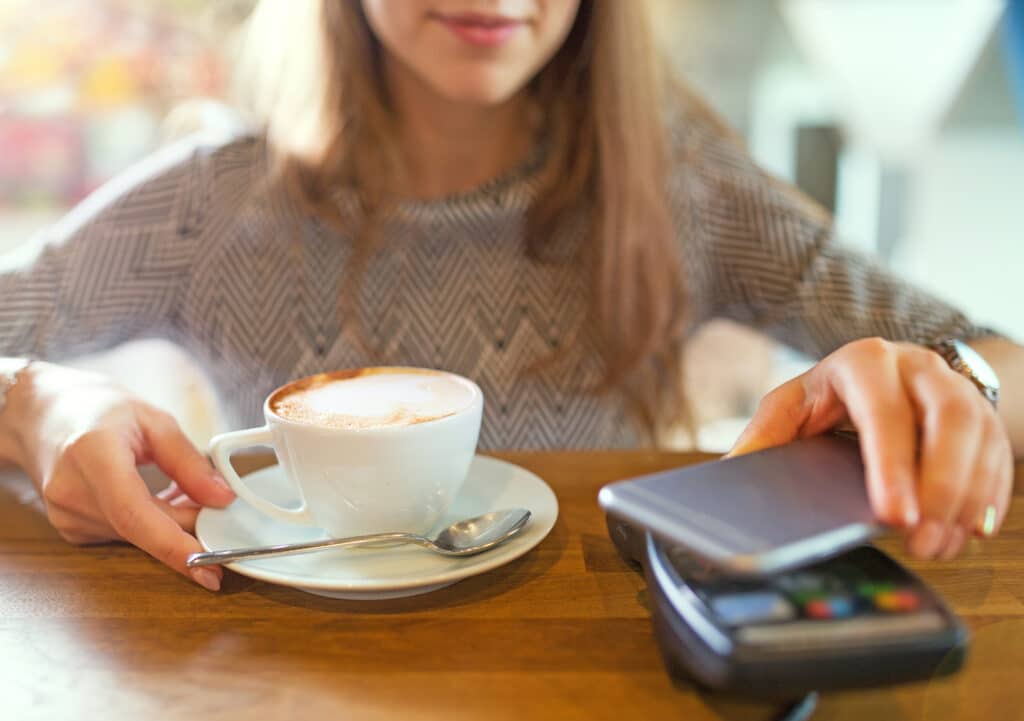 Ragazza che paga il cappuccino tramite app telefonica
