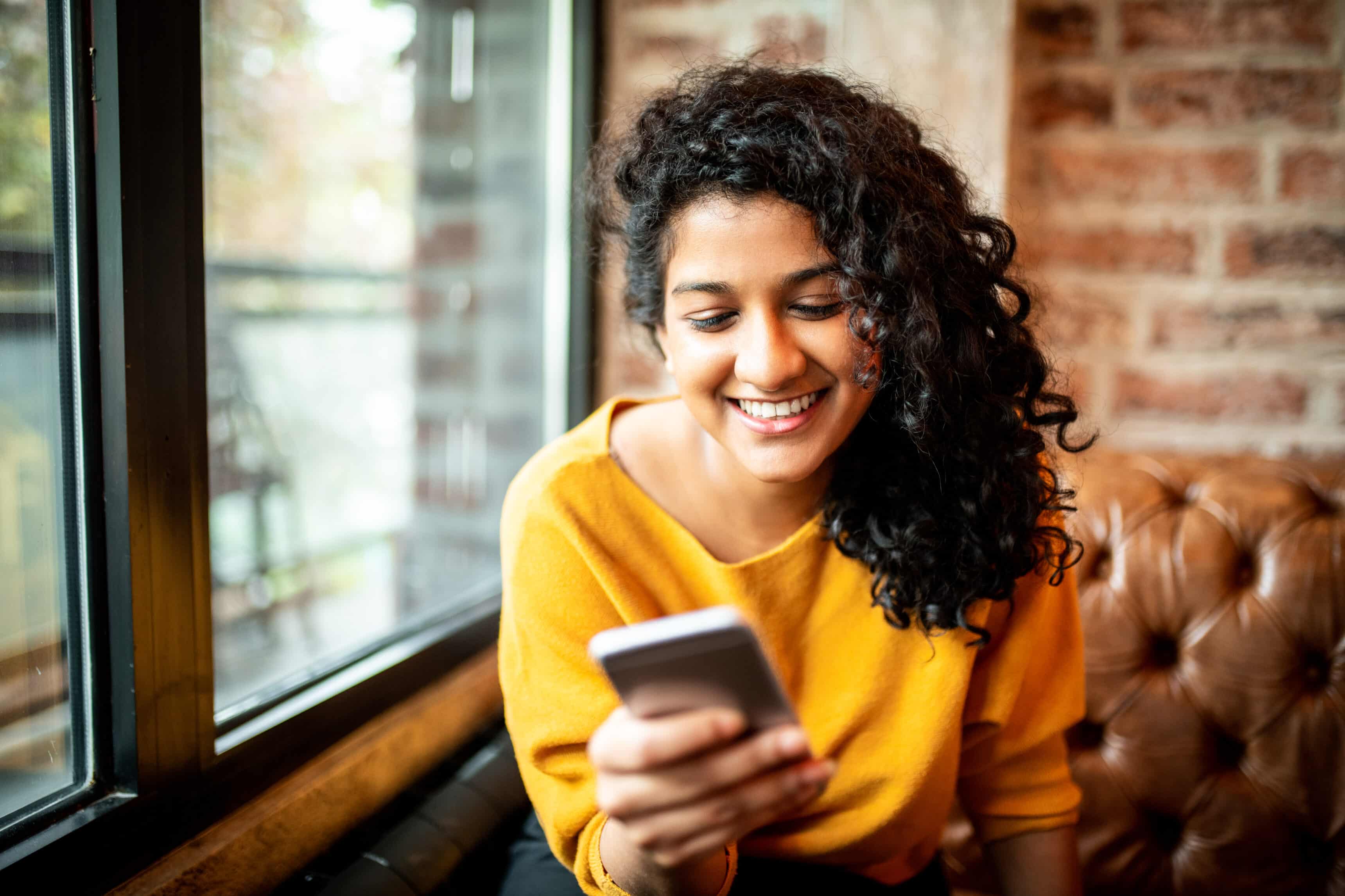 Una joven sonriente usando su teléfono celular